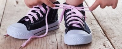 Child successfully ties shoes - closeup on feet and hands